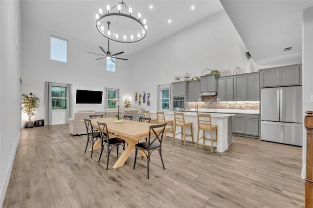 dining area with a towering ceiling, light wood-style flooring, a ceiling fan, and recessed lighting