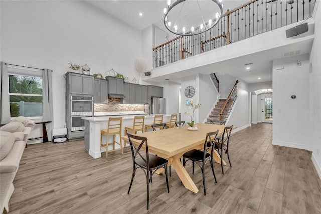 dining area featuring baseboards, visible vents, stairs, light wood-style floors, and a notable chandelier