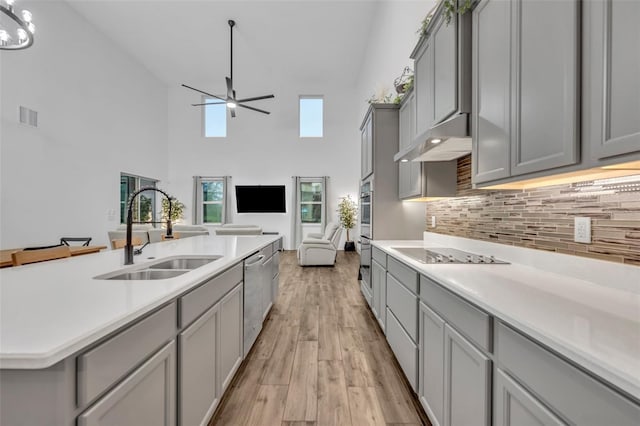 kitchen featuring under cabinet range hood, gray cabinetry, a sink, visible vents, and appliances with stainless steel finishes