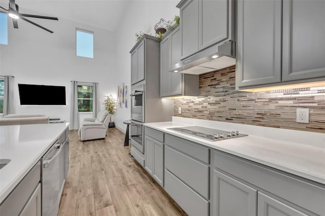 kitchen with black electric cooktop, under cabinet range hood, a healthy amount of sunlight, open floor plan, and gray cabinets