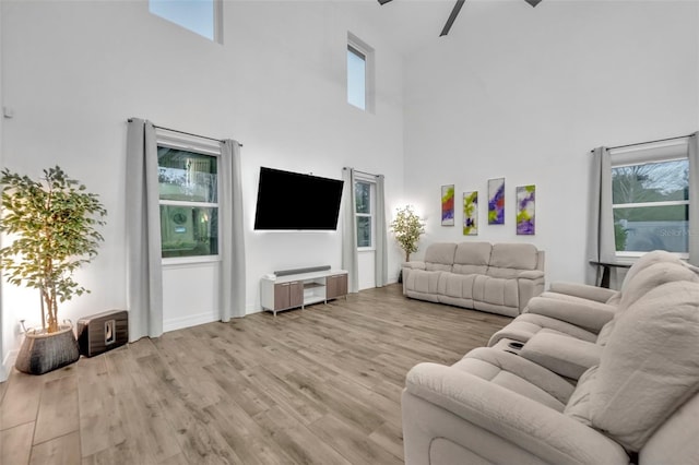 living room featuring light wood-style floors, ceiling fan, and a high ceiling