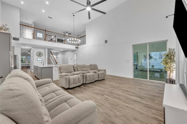 living room with ceiling fan, visible vents, baseboards, stairway, and light wood finished floors