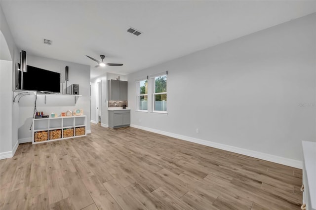 unfurnished living room featuring light wood-style floors, ceiling fan, visible vents, and baseboards