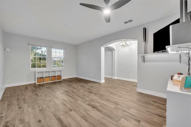 unfurnished living room with arched walkways, visible vents, light wood-style flooring, and baseboards