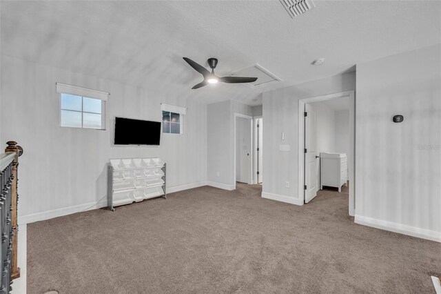 unfurnished living room featuring carpet, visible vents, a ceiling fan, attic access, and baseboards