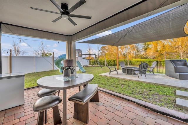 view of patio / terrace featuring an outdoor fire pit, a playground, and a fenced backyard