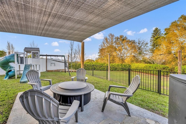 view of patio with an outdoor fire pit, a playground, and a fenced backyard