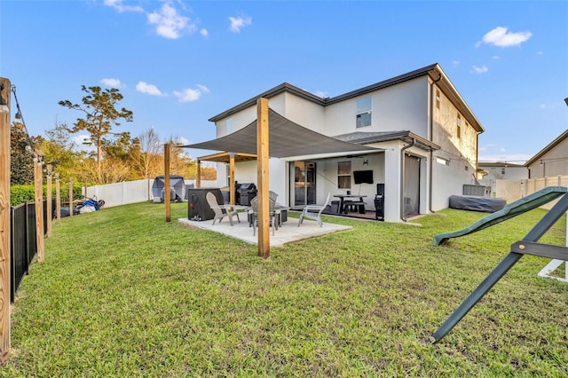 rear view of house with a patio, a lawn, a fenced backyard, and stucco siding