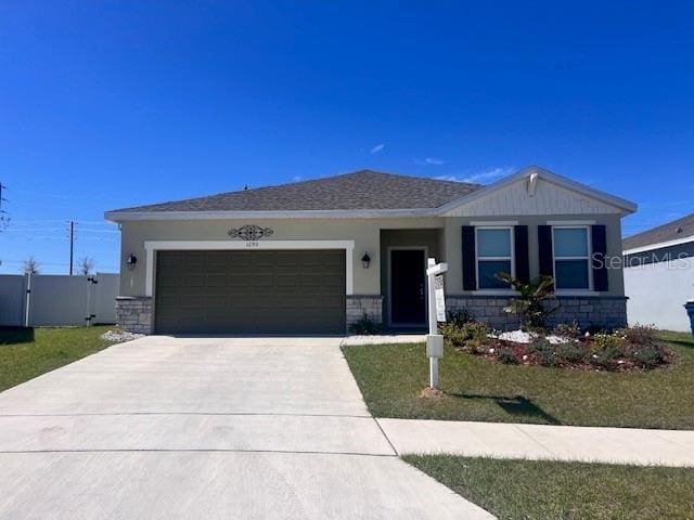 view of front of property featuring concrete driveway, stone siding, an attached garage, fence, and stucco siding