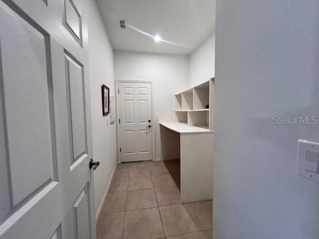 interior space with light tile patterned flooring, visible vents, and baseboards