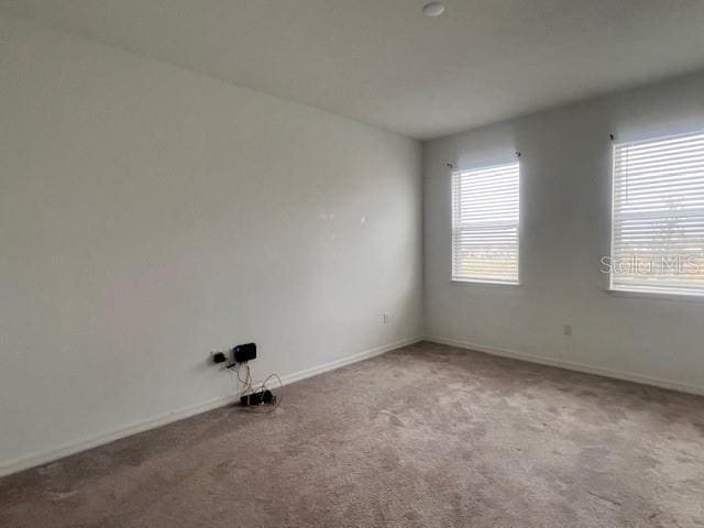 spare room featuring carpet and baseboards