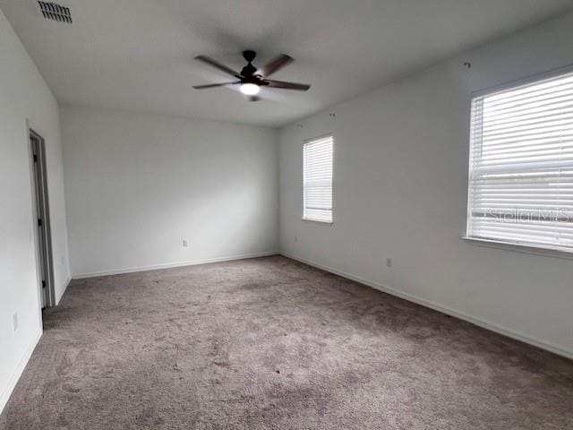 carpeted spare room with visible vents, ceiling fan, and baseboards