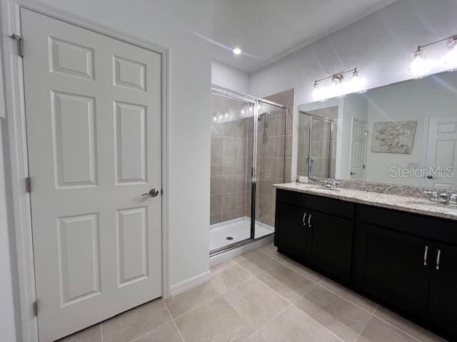 bathroom featuring double vanity, a sink, a shower stall, and tile patterned floors