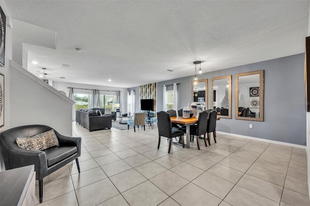 dining space featuring light tile patterned floors, baseboards, and a textured ceiling