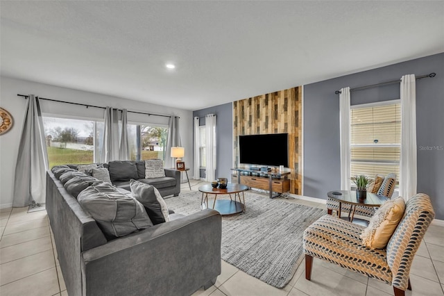 living room featuring an accent wall, light tile patterned floors, baseboards, and wood walls