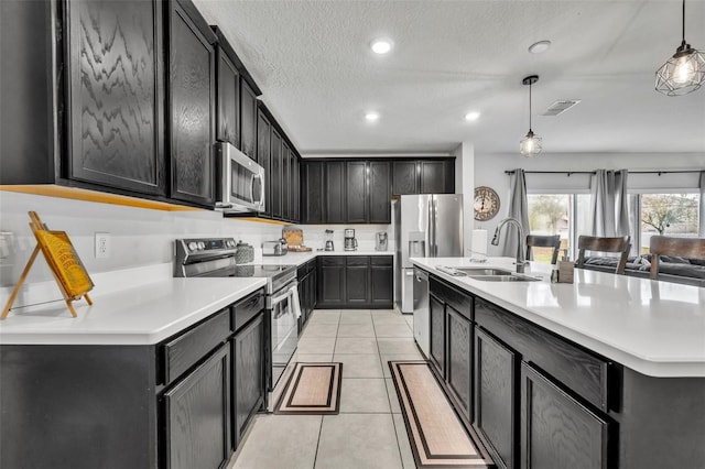 kitchen with visible vents, stainless steel appliances, dark cabinetry, and a sink