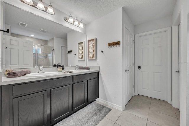 bathroom with tile patterned floors, visible vents, a stall shower, a sink, and a textured ceiling