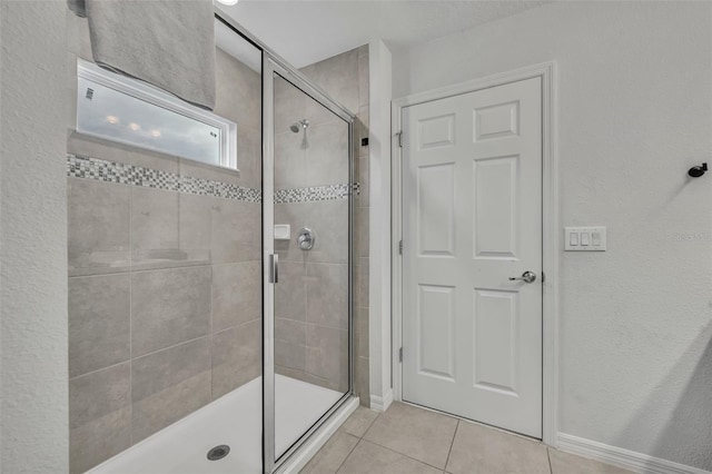 full bathroom with baseboards, a stall shower, and tile patterned flooring