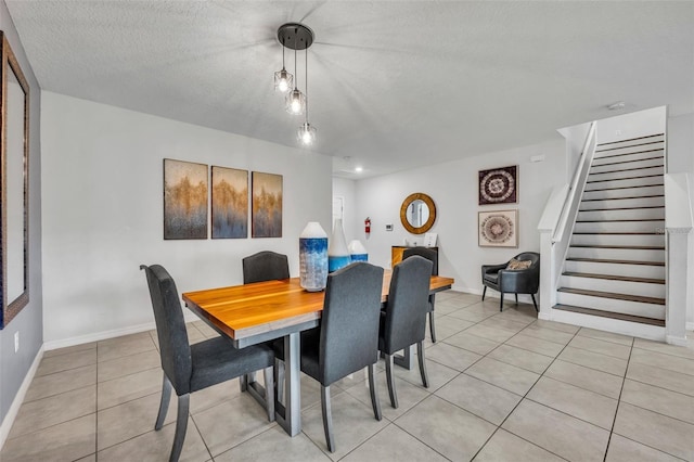 dining area with stairway, light tile patterned floors, baseboards, and a textured ceiling