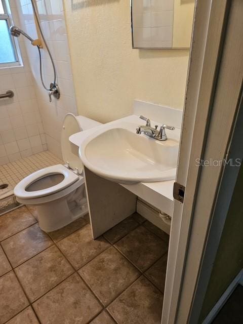 full bathroom with toilet, a stall shower, a sink, and tile patterned floors