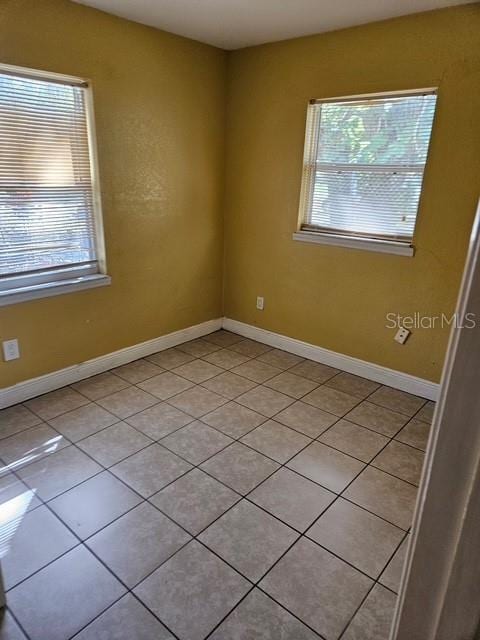 unfurnished room with light tile patterned floors and baseboards