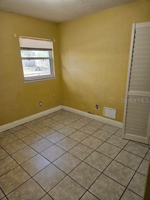 unfurnished room with baseboards and a textured ceiling