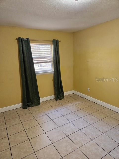 unfurnished room with baseboards and a textured ceiling