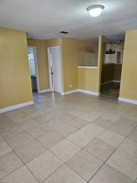 unfurnished room with visible vents, a textured ceiling, baseboards, and light tile patterned flooring