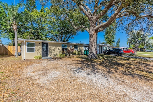 ranch-style home featuring stucco siding and fence