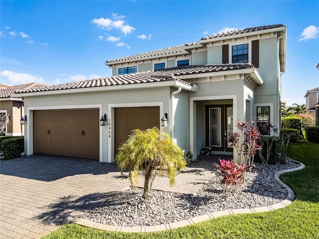 view of front of property featuring a garage, a tile roof, decorative driveway, and stucco siding