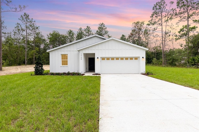 view of front of home featuring board and batten siding, a garage, driveway, and a front lawn