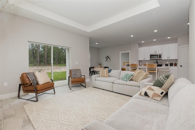 living room with baseboards, a tray ceiling, and recessed lighting