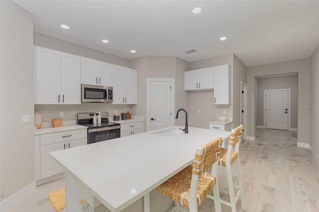 kitchen featuring a sink, stainless steel appliances, light countertops, and white cabinets