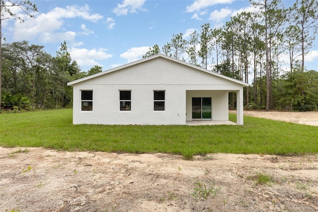 back of property with stucco siding, a patio, and a yard