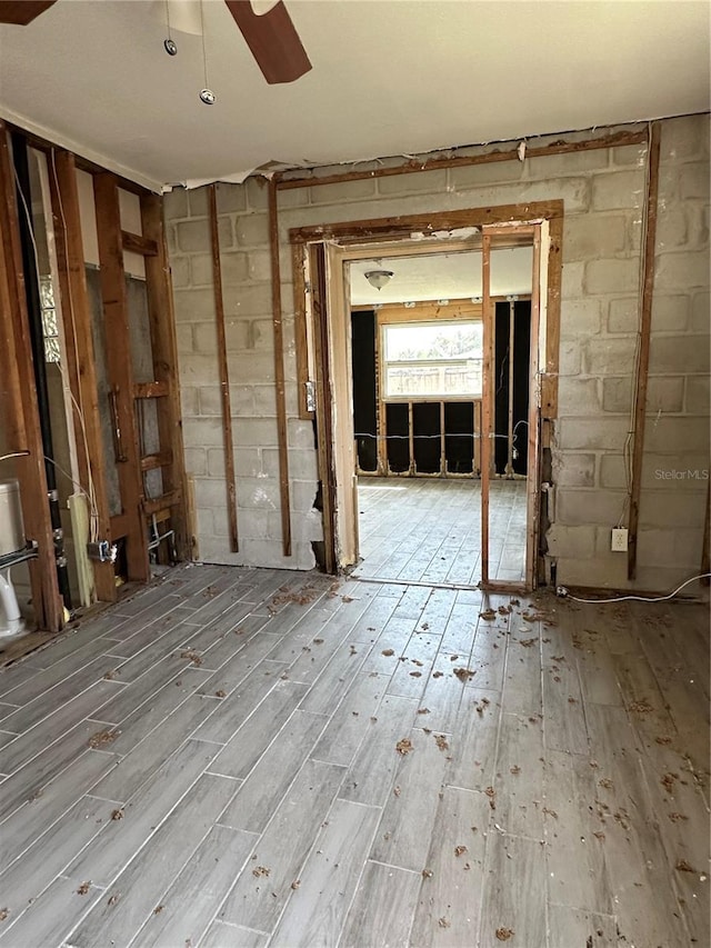 misc room featuring a ceiling fan, concrete block wall, and hardwood / wood-style flooring