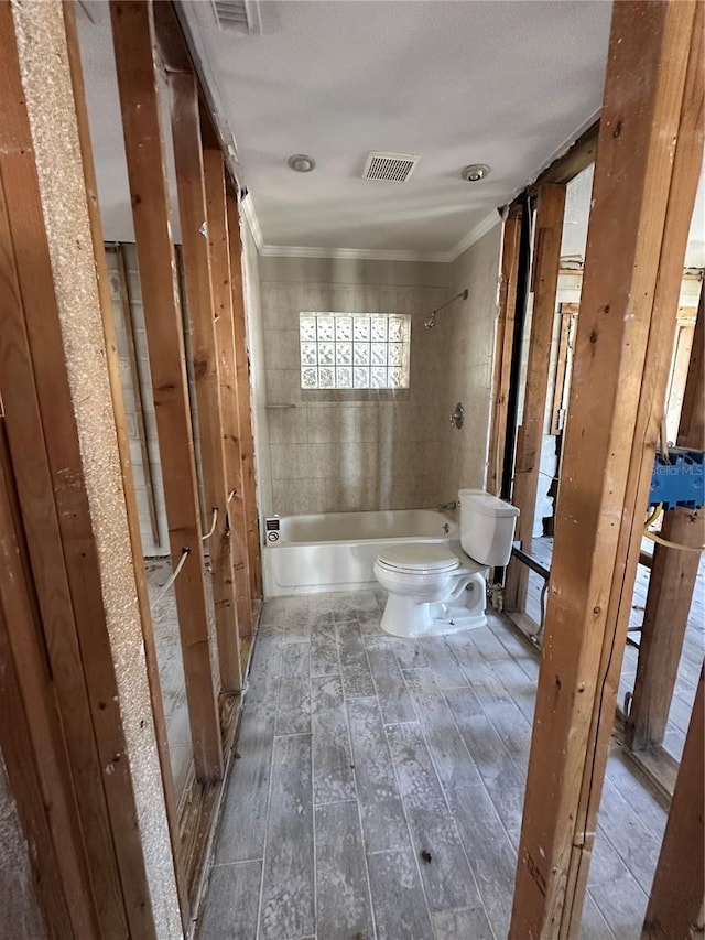 bathroom featuring crown molding, visible vents, toilet, shower / tub combination, and wood finished floors