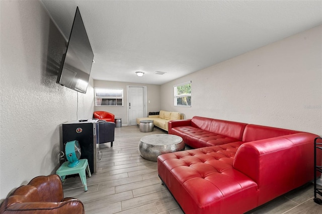 living room featuring a textured ceiling, a textured wall, and wood finish floors