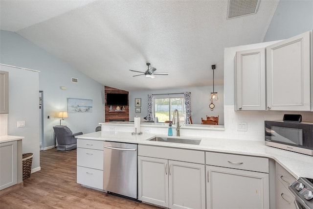 kitchen featuring visible vents, appliances with stainless steel finishes, open floor plan, a peninsula, and a sink