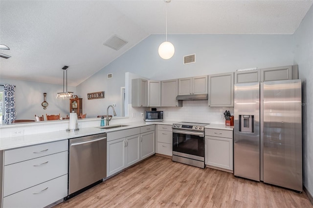 kitchen featuring stainless steel appliances, light countertops, gray cabinetry, a sink, and under cabinet range hood