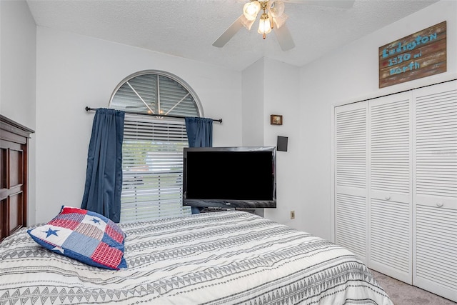 carpeted bedroom with a textured ceiling, a ceiling fan, and a closet