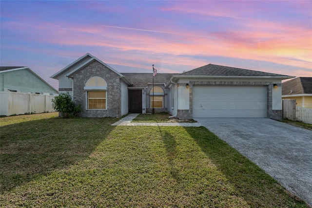 ranch-style home with a yard, an attached garage, fence, and driveway