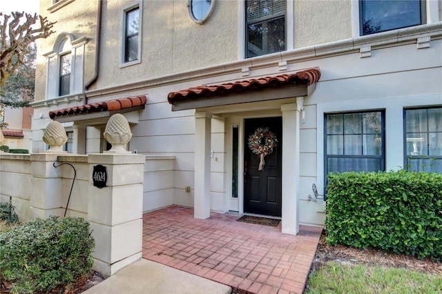 doorway to property with a tile roof and stucco siding