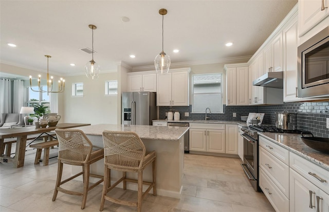 kitchen featuring under cabinet range hood, tasteful backsplash, high quality appliances, and a center island