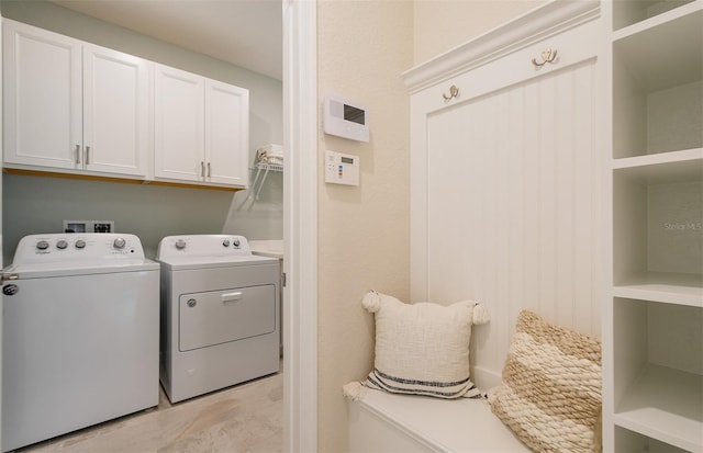 clothes washing area with washing machine and dryer and cabinet space