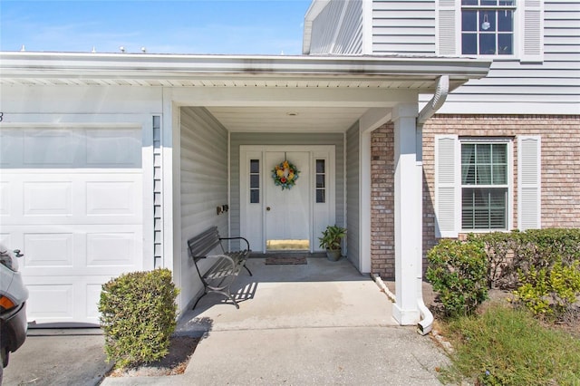 property entrance featuring an attached garage and brick siding