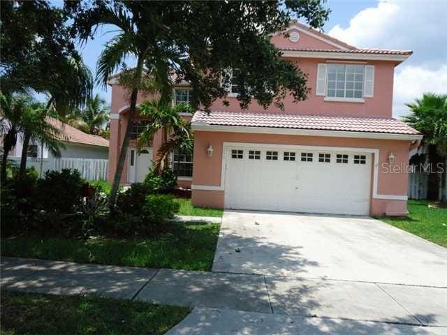 view of front of house with a garage, a tile roof, concrete driveway, and stucco siding