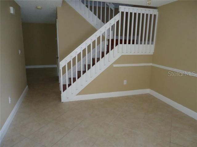 stairway with baseboards and tile patterned floors