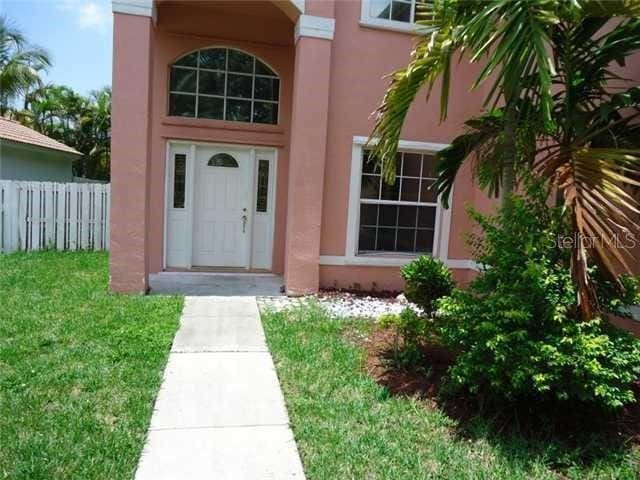 view of exterior entry featuring a lawn, fence, and stucco siding