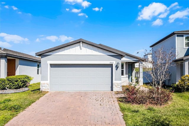 single story home with stone siding, decorative driveway, board and batten siding, and an attached garage