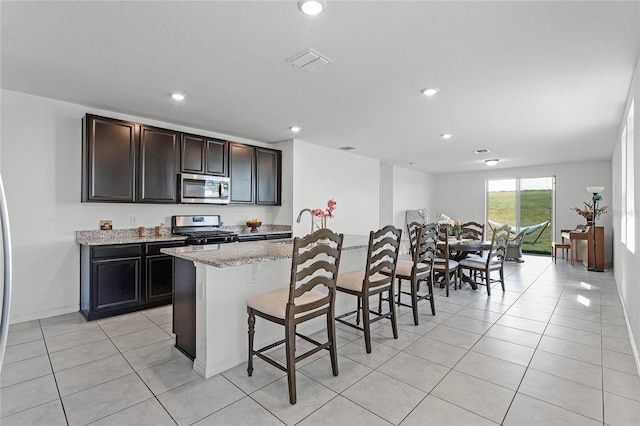 kitchen featuring visible vents, appliances with stainless steel finishes, a breakfast bar area, and light tile patterned flooring